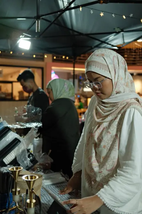 A Brewprint barista taking an order on a tablet at the night bazaar stall