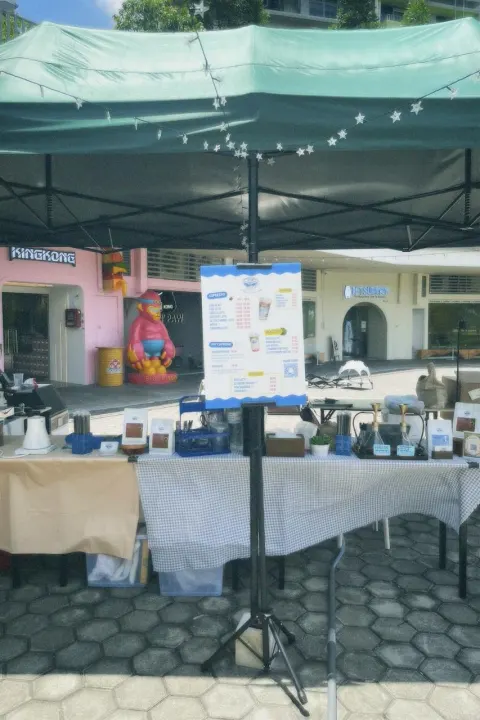 Brewprint Coffee pop-up stall under a green canopy with star string lights, a menu board and the coffee and matcha set-up