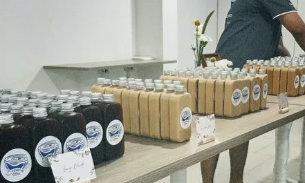 Bottled long blacks and lattes lined up with handwritten drink labels
